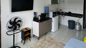 Una cocina moderna con televisor de pantalla plana, cafetera, microondas y estufa a gas.