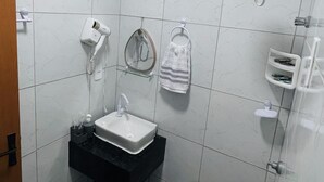 Un baño con lavamanos, espejo, secador de pelo, toallero y ducha.