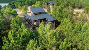 Eine Hütte mit einer großen Terrasse und einer überdachten Veranda, umgeben von dichtem Wald.