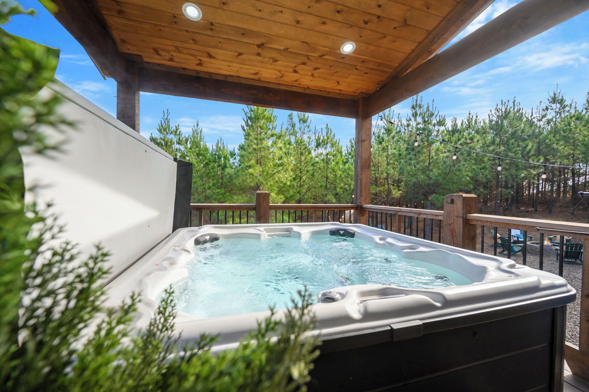 A hot tub on a wooden deck with a view of trees.