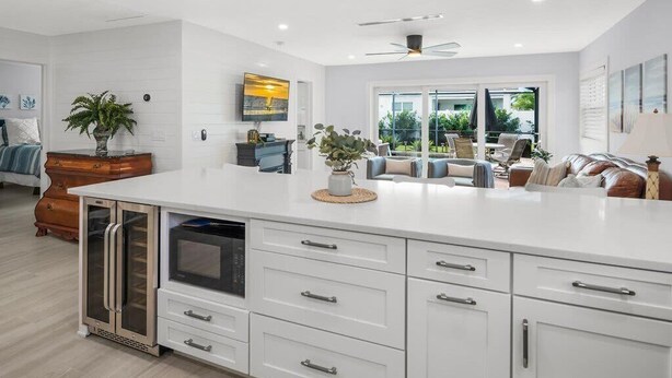 A modern kitchen with white cabinetry, a built-in oven, and a large island with drawers. - Walk to Beach! Family Pool Home in Naples (Naples)