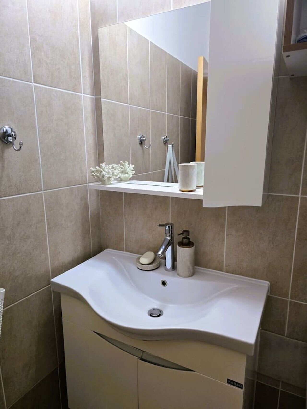 A bathroom with a white sink, a mirror, and a towel rack.