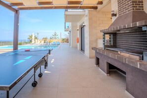 An outdoor pool area with a ping pong table, a barbecue grill, and a view of the sea. - Villa Shlomo-Pool-Near the beach-Kids playground (Plaka)