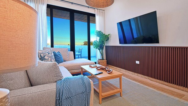 A modern living room with a sofa, a coffee table, and a television mounted on the wall. - Modern 2BR Apartment Near the Malecón | Balcony • Rooftop BBQ (La Paz)