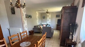 Ein Essbereich mit einem Holztisch und Stühlen, einer Deckenleuchte und einer Küche im Hintergrund.