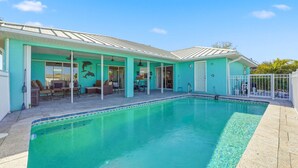 A swimming pool with a covered patio area, a door leading to a covered entryway, and a fenced poolside area. - Waterfront Villa with Pool, Dock and Gulf Access (Port Charlotte)