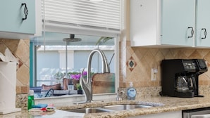 A kitchen with a granite countertop, stainless steel sink, and a coffee maker. - Waterfront Villa with Pool, Dock and Gulf Access (Port Charlotte)