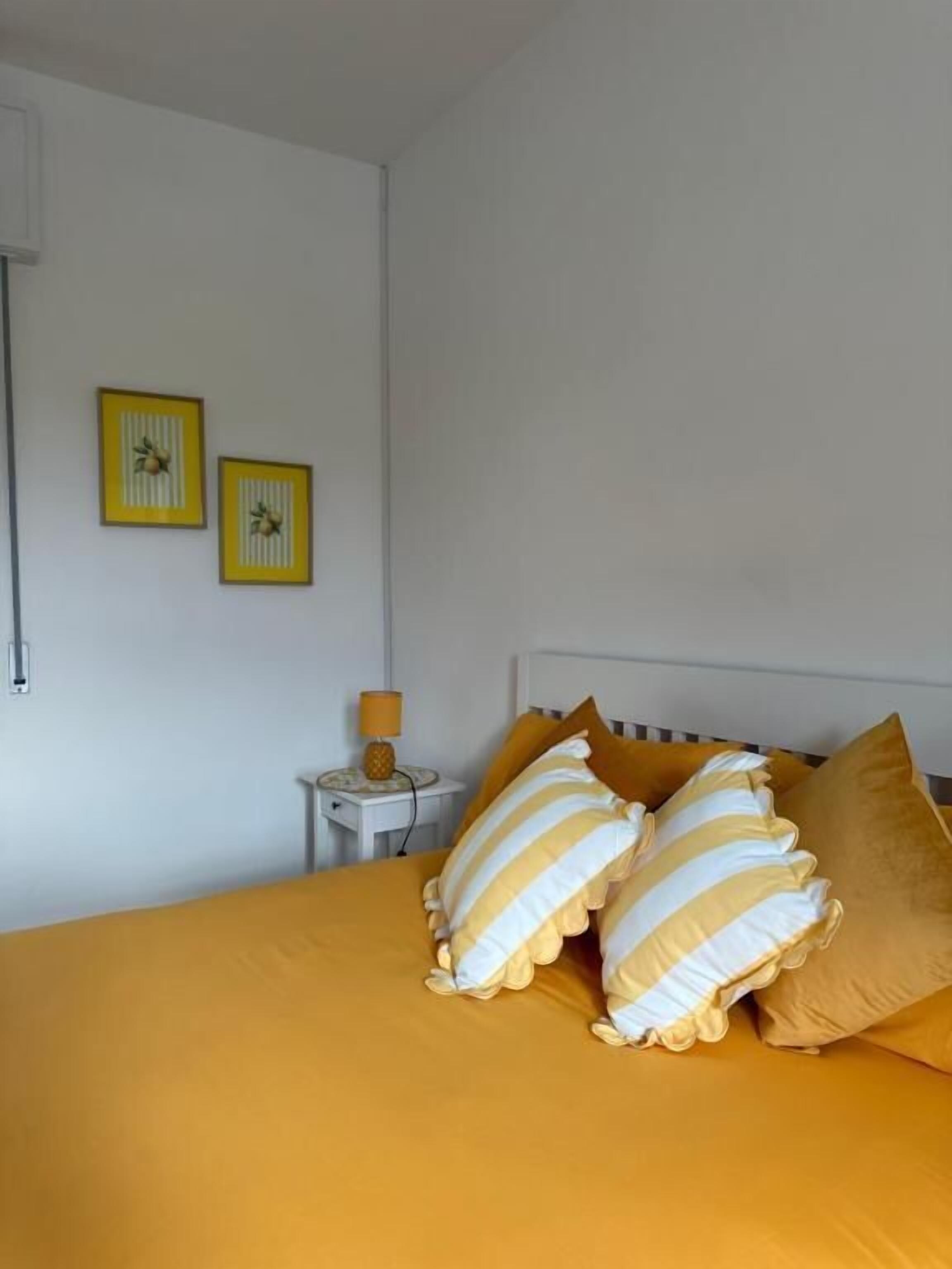 Una camera da letto con un letto, due quadri incorniciati, un comodino con una lampada e una finestra.