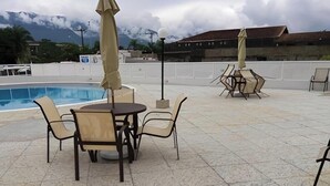 Ein Außenpoolbereich mit einem runden Tisch und Stühlen, umgeben von Sonnenschirmen.