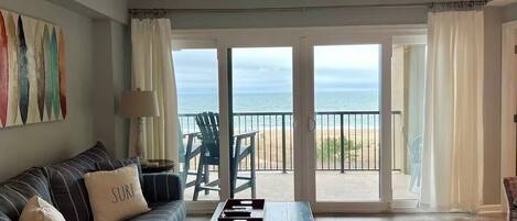 Un salón con sofá, una mesa de centro y vistas a la playa a través de amplios ventanales.