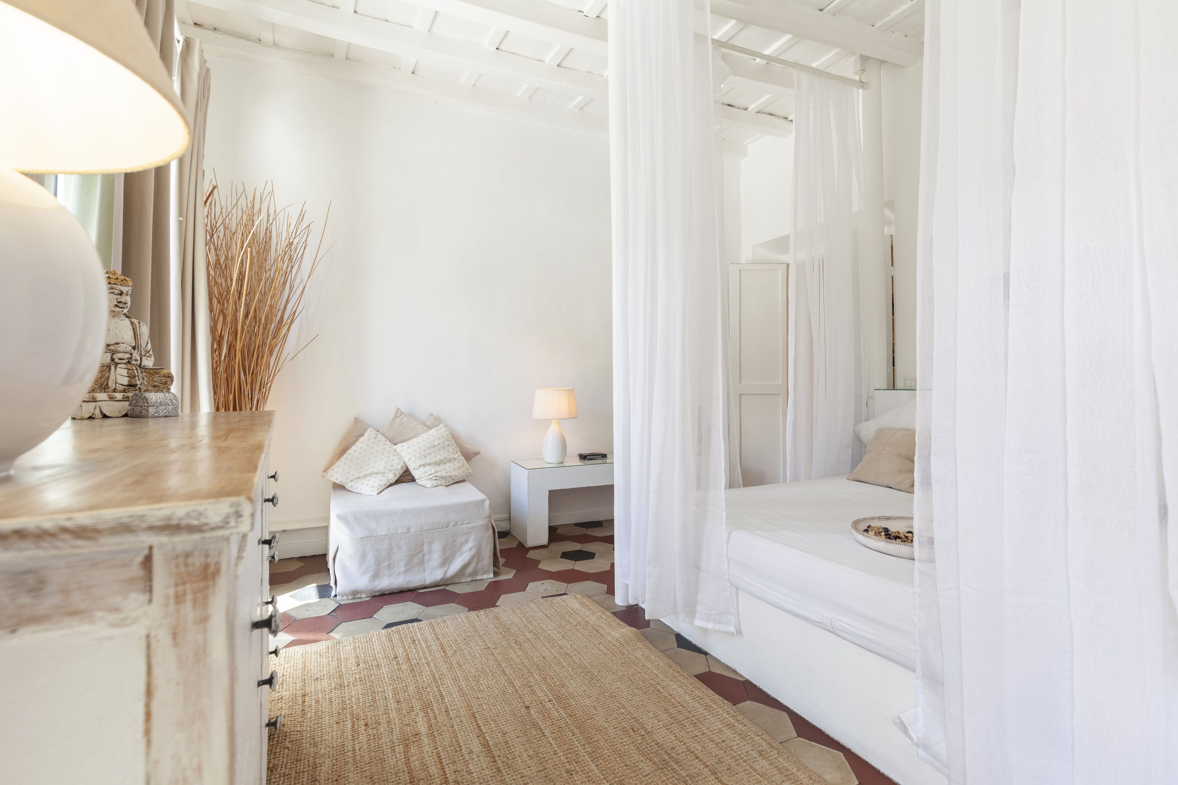 A white bedroom with a bed, bedside table, and a nightstand.