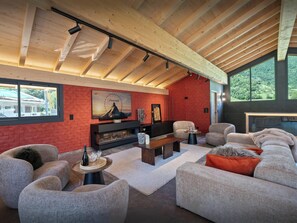 A modern living room with a fireplace, comfortable seating, and large windows offering a view of the outdoors. - Chalet Tyron - The Alps at all season in a rural setting - OVO Network (Val de Chaise)