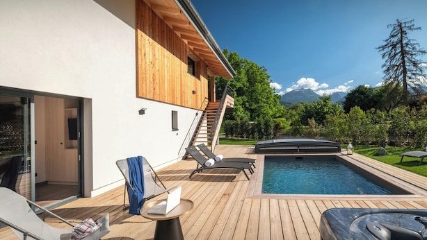 Ett modernt utomhusområde med pool, solstolar, ett bubbelbad och ett trädäck.