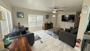 Ein Wohnzimmer mit Deckenventilator, Fernseher und Kamin.