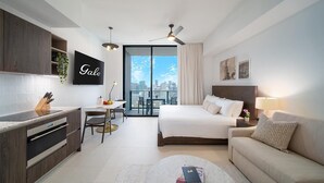 Ett modernt hotellrum med en säng, en soffa, ett skrivbord och en balkong med utsikt över staden.