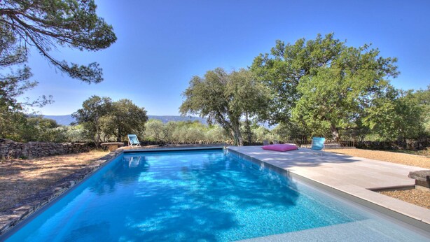A rectangular swimming pool with clear blue water, surrounded by a stone wall and trees. - Proven al Bergerie With Pool Sleeps 4 Gordes (Gordes)