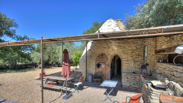 A rustic stone building with a wooden door and a small window, surrounded by gravel and trees. - Proven al Bergerie With Pool Sleeps 4 Gordes (Gordes)