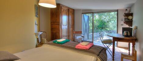 Un dormitorio con cama, una silla, una mesa y una ventana.