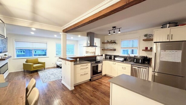 Una cucina moderna con pavimento in legno, mobili bianchi ed elettrodomestici in acciaio inossidabile.