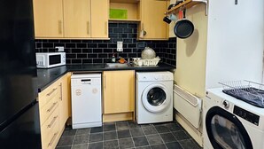 Une cuisine compacte équipée d’un lave-linge, d’un four à micro-ondes et d’un évier.