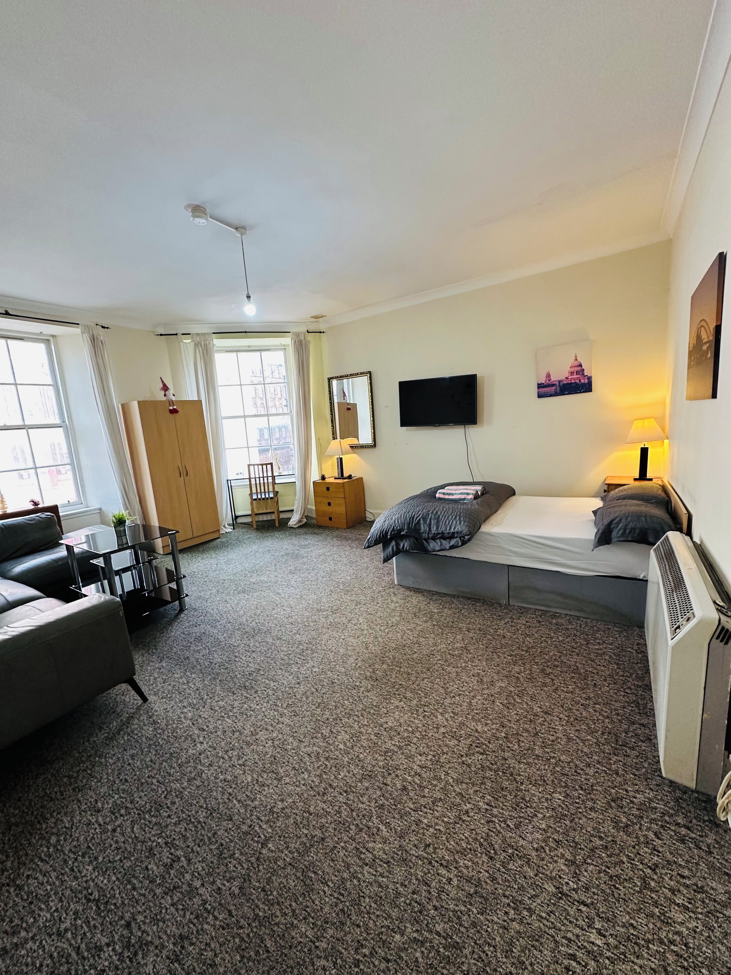 Une chambre d’hôtel comprenant un lit, un bureau, une chaise, une armoire, une télévision et une fenêtre.