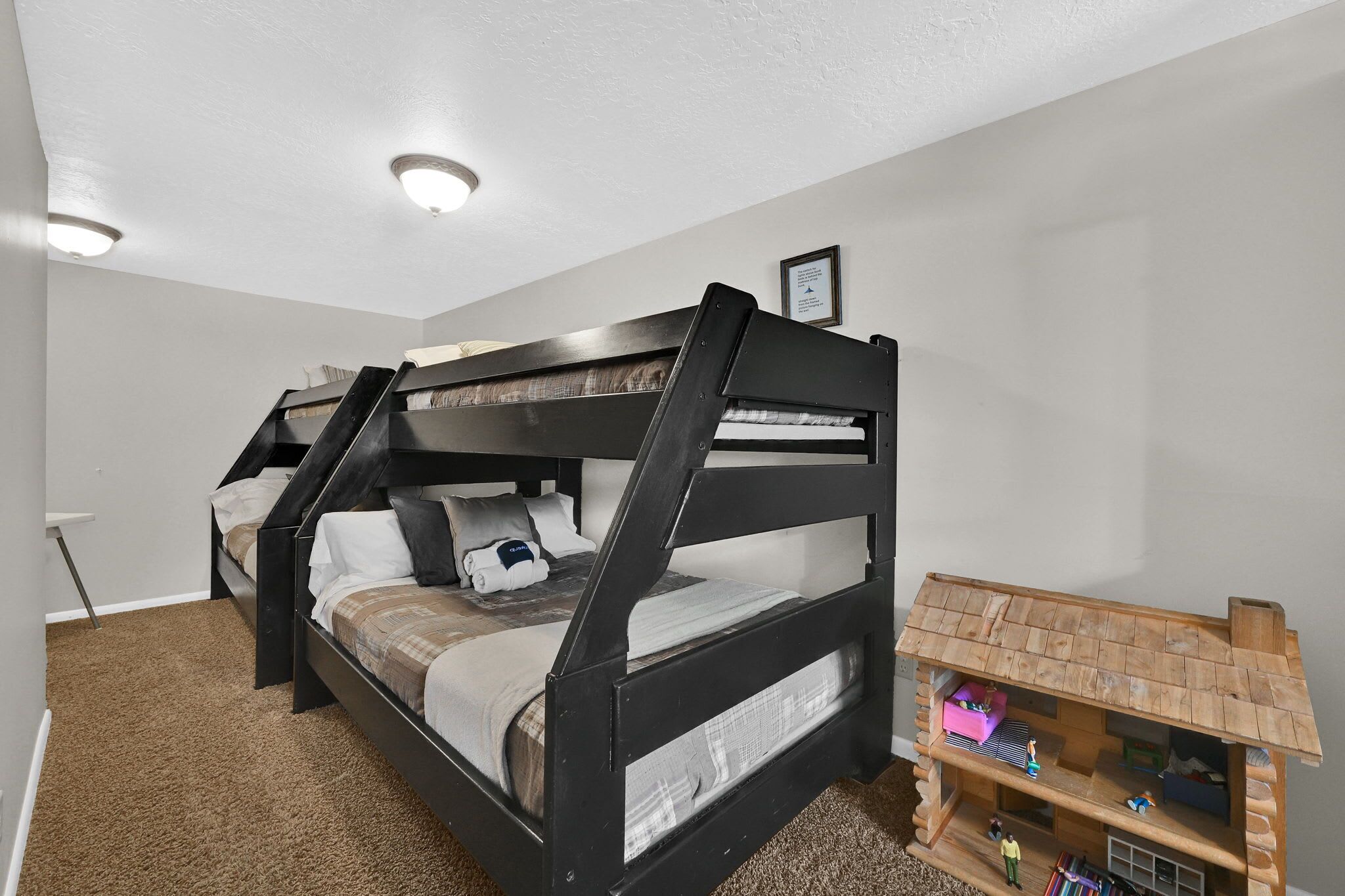 A bunk bed with a lower bunk, a wooden headboard, and a small wooden shelf with toys.