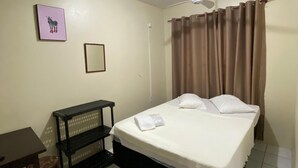 A bedroom with a bed, a desk, a chair, a ceiling fan, and a picture on the wall. - Pousada Estação Ferrugem (Garopaba)