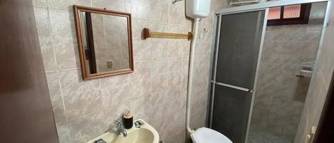 Un baño con lavamanos, inodoro y zona de ducha.