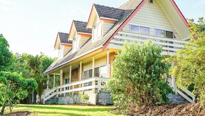 Une maison à deux étages avec un porche, un escalier et un jardin bien entretenu.