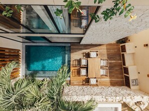 A modern outdoor pool area with a glass ceiling, wooden deck, and seating. - Luxe Villa 10p, Grill, 2 Private Pools w/Concierge (Tulum)