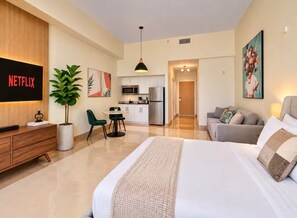A modern hotel room with a bed, a desk, a TV displaying 'NETFLIX', a dining area, and a kitchenette. - Brickell Studio: Free Parking, Pool & Private Patio (Miami)