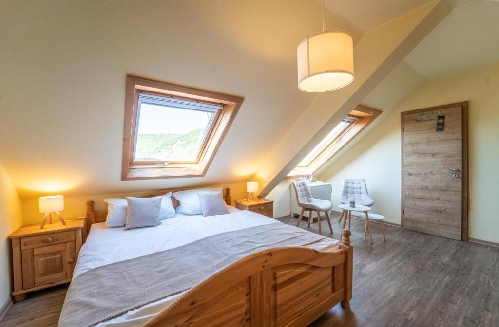 Ein Schlafzimmer mit einem großen Bett, zwei Nachttischen mit Lampen, einem Sessel, einem Schreibtisch und einer Tür.