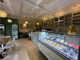A restaurant interior with a central ice cream display, wooden ceiling, and green walls.