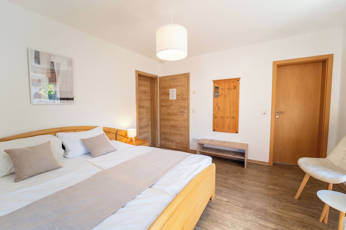 Une chambre à coucher avec un lit, des tables de chevet, un banc, une chaise et des portes en bois.