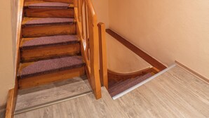 Un escalier en bois, doté d’une rampe et de marches recouvertes de moquette, menant à un palier.