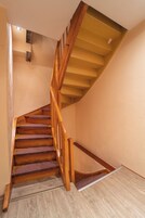 A wooden staircase with a handrail and carpeted steps leading to a landing.