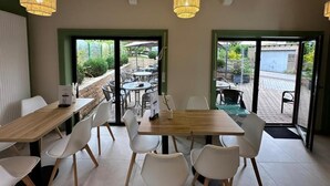 L’intérieur d’un café, avec des tables et des chaises, un comptoir en bois et des lampes suspendues.