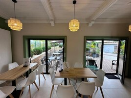 A cafe interior with tables and chairs, a wooden counter, and hanging lights.
