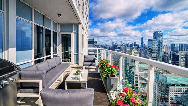 A rooftop terrace with a sofa, table, and grill, overlooking a city skyline. - Skyline Penthouse - CN Tower Downtown (Toronto)