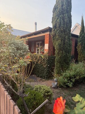 A brick house with a garden, a tall tree, and a statue. - Towncottage Tenterfield Stay with Scenic Views (Tenterfield)