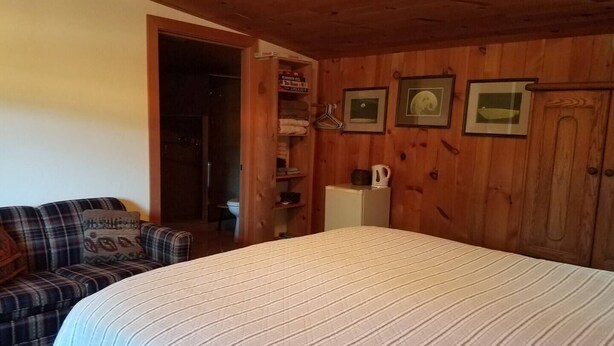 A cozy room with a bed, a wooden wardrobe, a small kitchenette, and a plaid sofa. - Ruch Refuge in Jacksonville (Jacksonville)