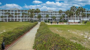 Un hotel con varios pisos, un camino central y palmeras.
