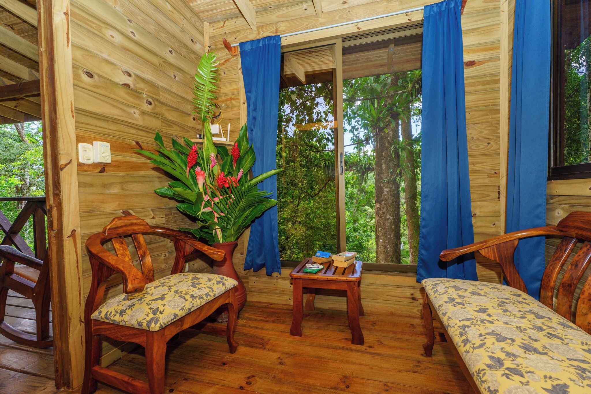 L’intérieur d’une cabane en bois, avec deux chaises en bois, une petite table et un banc.