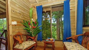 A wooden cabin interior with two wooden chairs, a small table, and a bench. - Peaceful Jungle Cabin at Ginger Retreat with River Sounds & Fast Internet (Quepos)