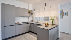 Una cucina moderna con mobili grigi, un'isola centrale e luci a sospensione.