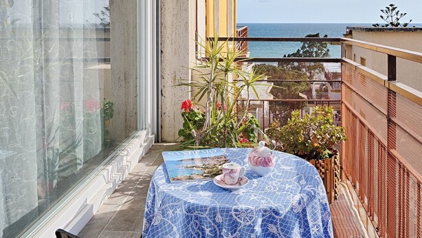Un balcone con un tavolo apparecchiato per due, con vista su un corpo d'acqua.