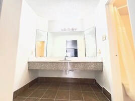 Un baño con lavamanos, espejo y suelo de baldosas.