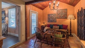 A cozy living room with a wooden ceiling, a fireplace, a sofa with colorful cushions, and a chandelier. - Chile Roja Downright Comfort, Mexico Style (Comfort)