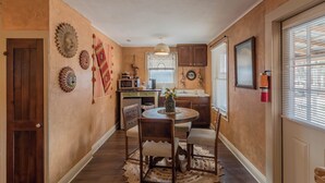 A compact kitchen with a dining area, featuring a round table, chairs, and a small island. - Chile Roja Downright Comfort, Mexico Style (Comfort)