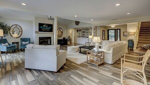 A spacious living room with a fireplace, white sofas, and a dining area with a table and chairs. - Spacious 4BR home in Sea Pines, Hilton Head Island, sleeps 10 comfortably. (Hilton Head Island)